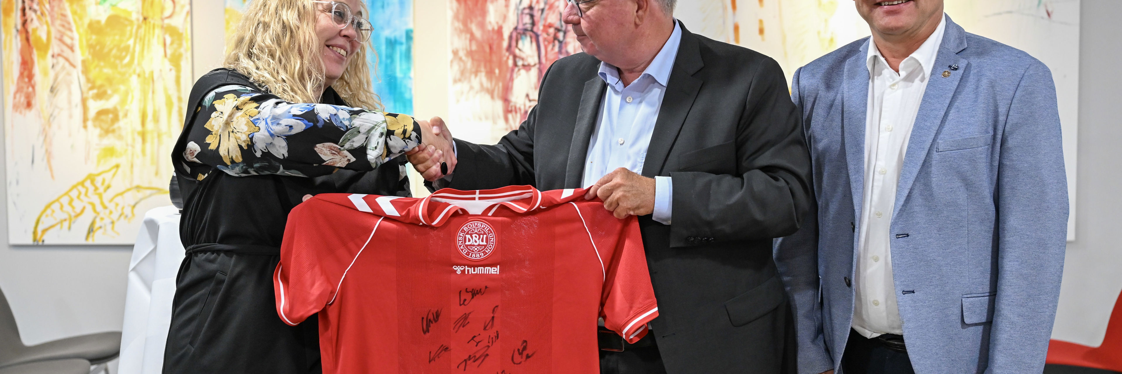 Borgmester i Randers Kommune, Rosa Lykke Yde, formand for DBU, Jesper Møller og formand DBU Jylland, Ole Ladefoged skriver under på aftalen (på foto fra venstre til højre). Inden da modtog borgmesteren en signeret landsholdtrøje i gave af DBU. Foto: Randers Kommune